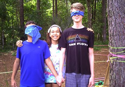 Teens with blindfold and one smiling at a retreat.
